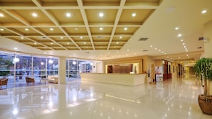 Un hall d’entrée spacieux comprenant un comptoir d’accueil, un espace salon et de grandes fenêtres donnant sur l’extérieur.