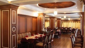 Un comedor formal con paneles de madera, candelabros y una larga mesa dispuesta para una comida.