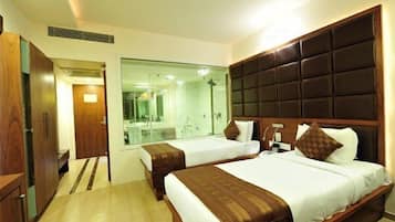 A hotel room with two beds, a large mirror, and a wooden headboard.