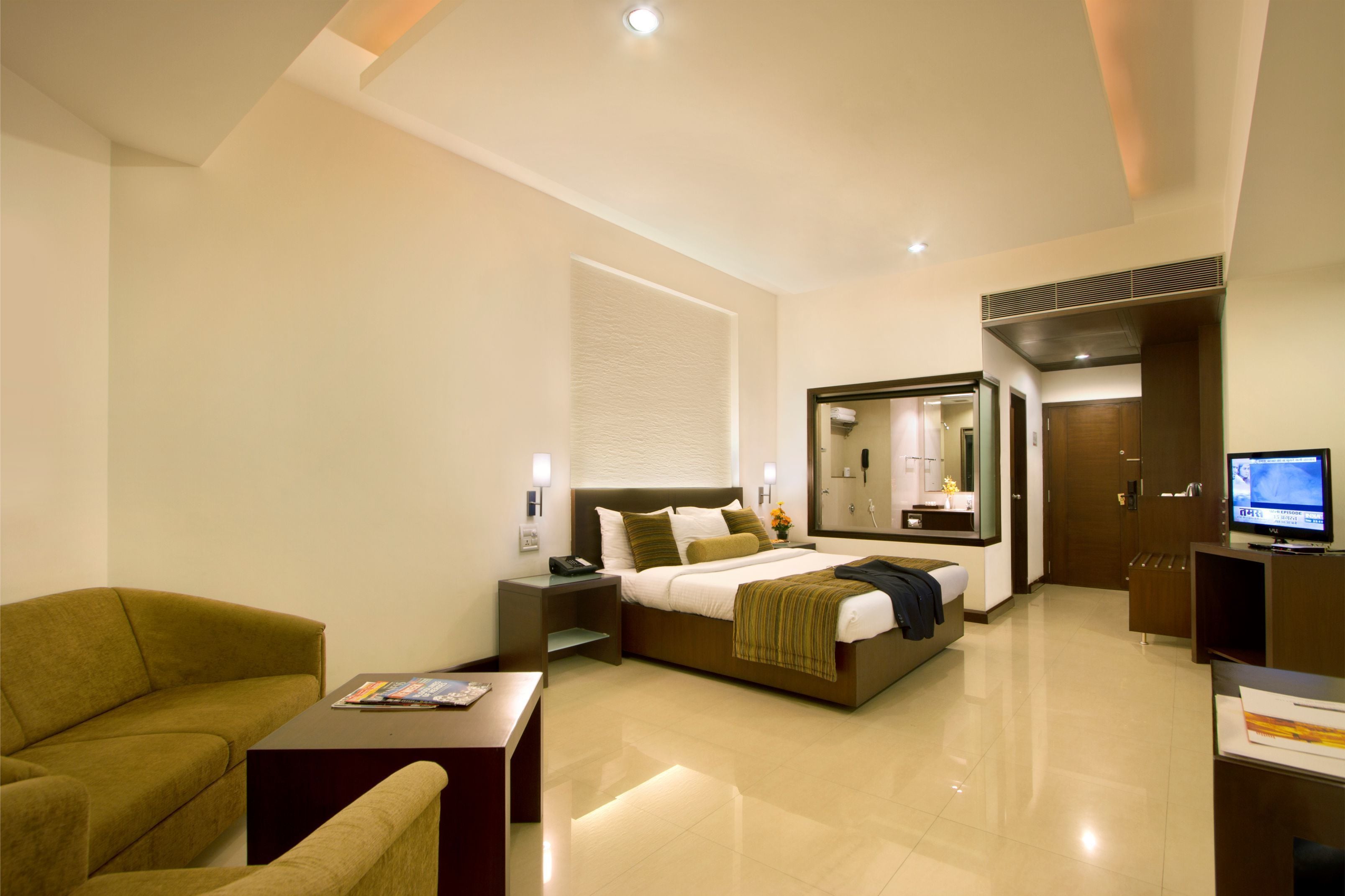 Una habitación de hotel moderna con una cama grande, un sofá, un televisor y un escritorio.