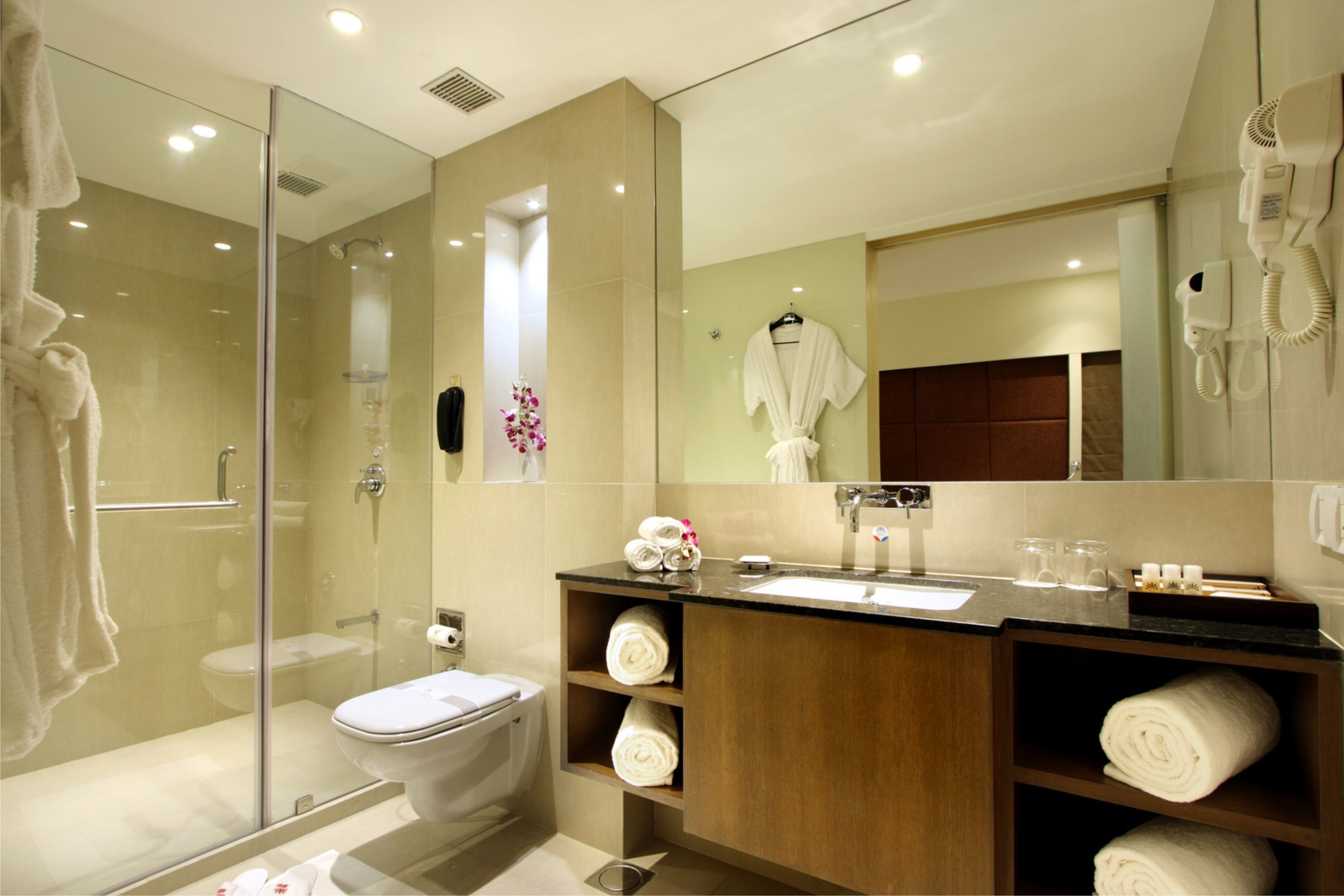 Un baño moderno con ducha acristalada, lavamanos con tocador y un espejo grande.