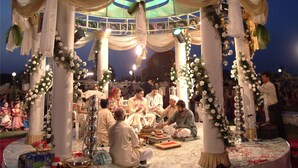 A wedding ceremony with a decorated gazebo and guests seated around a table. - Hotel Express Residency (Vadodara)