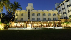 A hotel with a modern architectural design, featuring multiple balconies and a well-lit outdoor seating area. - Hotel Express Residency (Vadodara)