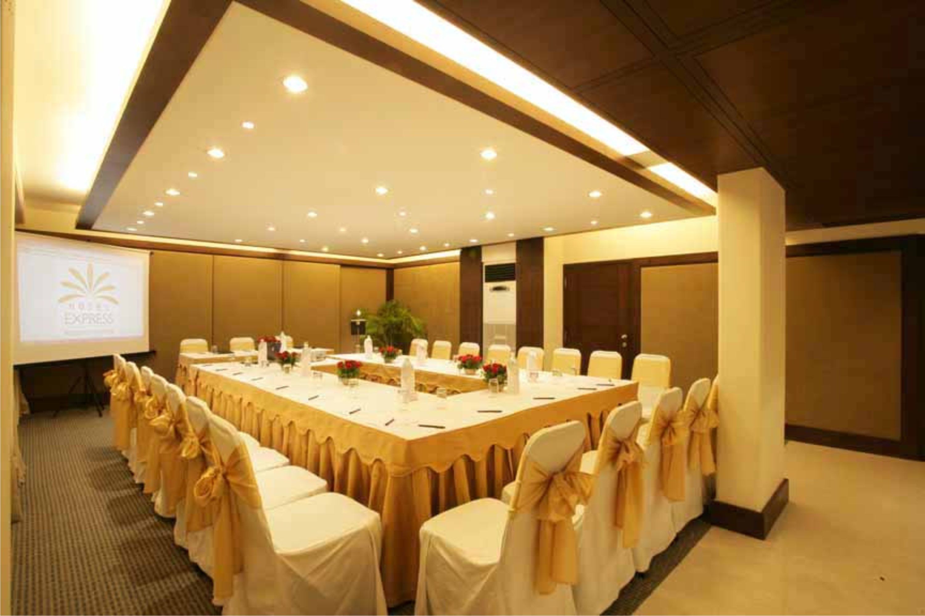 A conference room with a long table, chairs, and a projector screen.