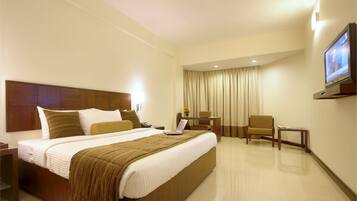 A hotel room with a large bed, a desk, a chair, and a television on the wall.