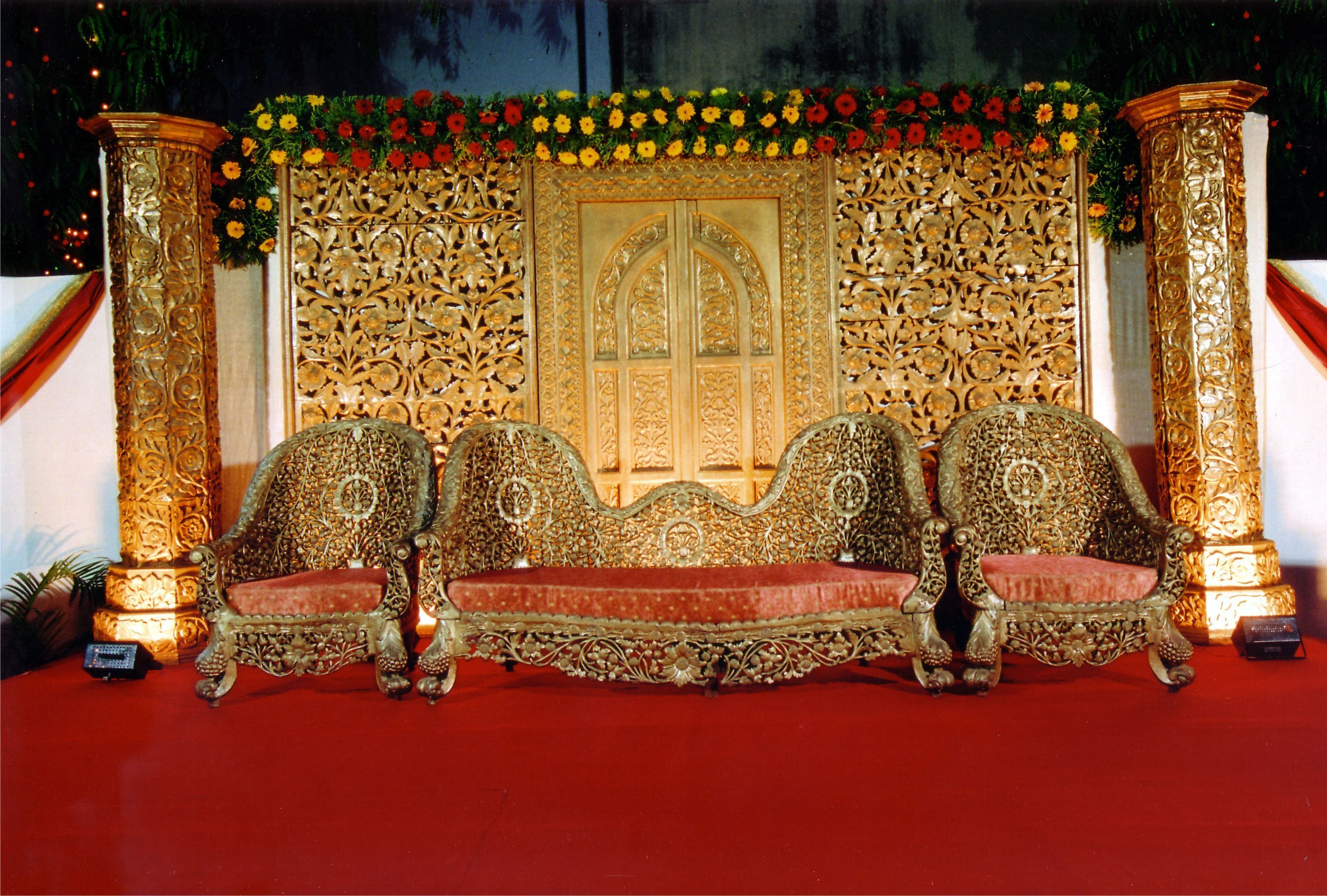 Un escenario lujoso con sillas doradas ornamentadas y un decorado llamativo.