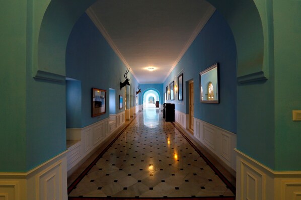 A hallway with blue walls, white wainscoting, and a patterned floor. - The Lallgarh Palace - A Heritage Hotel (Bikaner)