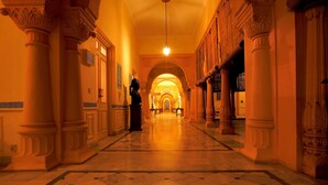 A grand hallway with ornate columns, a chandelier, and a marble floor. - The Lallgarh Palace - A Heritage Hotel (Bikaner)