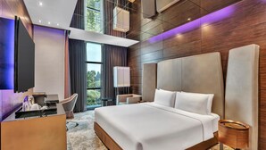 Une chambre d’hôtel moderne dotée d’un grand lit, d’un bureau avec un téléviseur à écran plat, d’une chaise et offrant une vue sur l’extérieur.