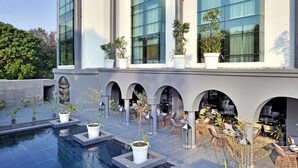Un bâtiment moderne doté de grandes fenêtres, d’une piscine et d’espaces extérieurs aménagés avec des plantes en pot.