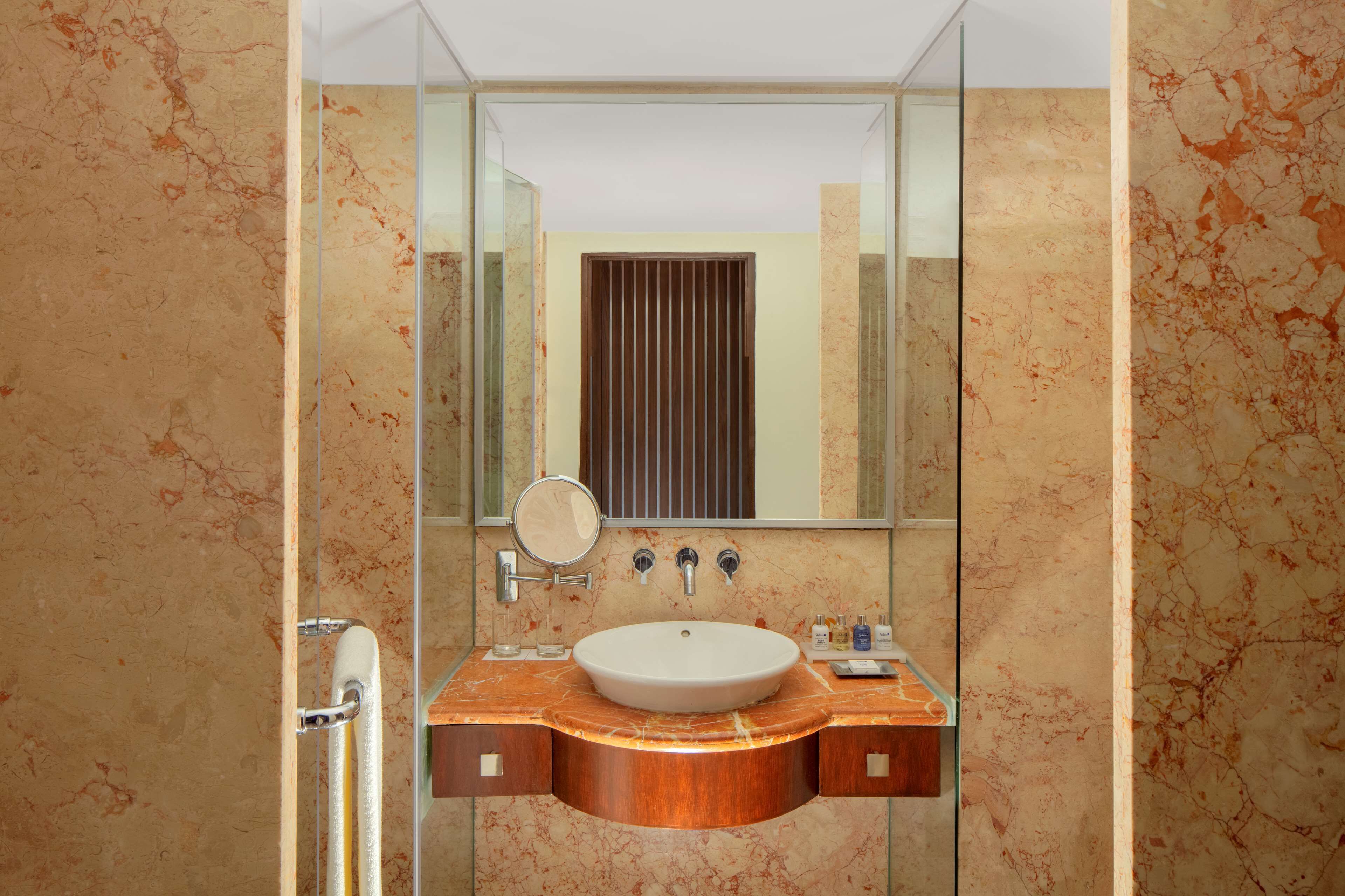 A bathroom with a marble sink, a mirror, and a glass shower enclosure.
