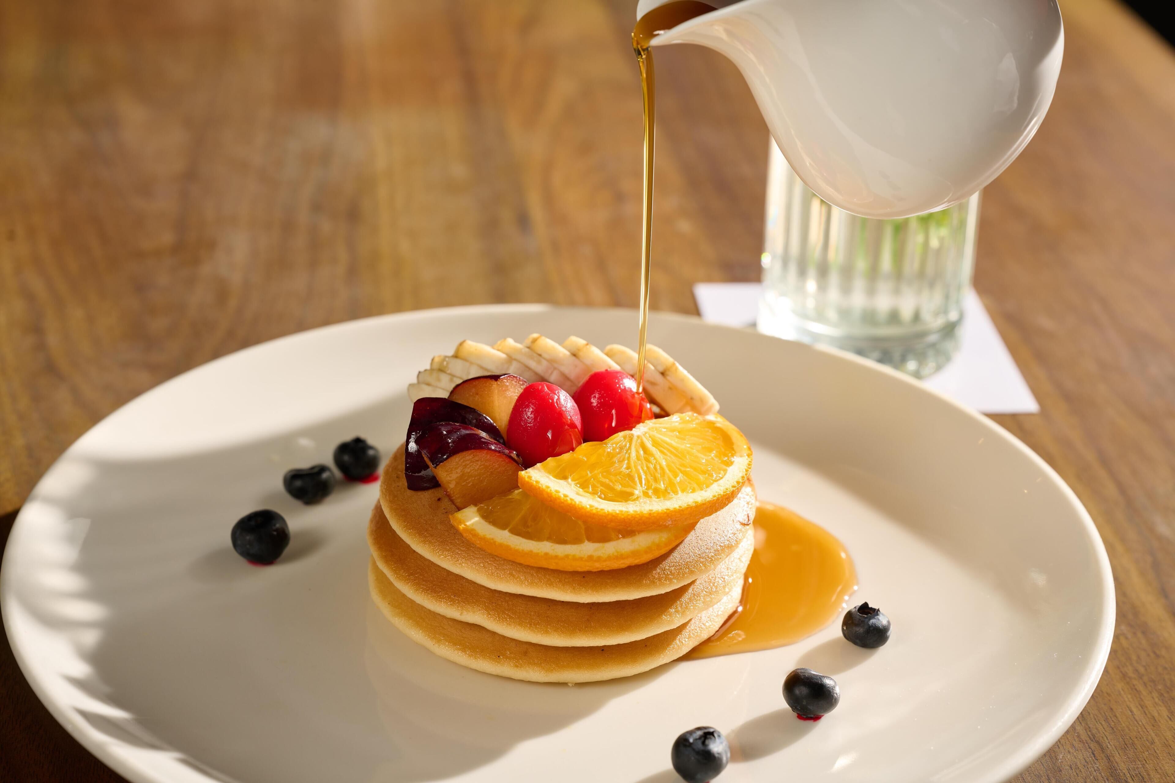 A stack of pancakes with fruit and syrup on a plate.
