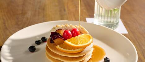 A stack of pancakes with fruit and syrup on a plate.