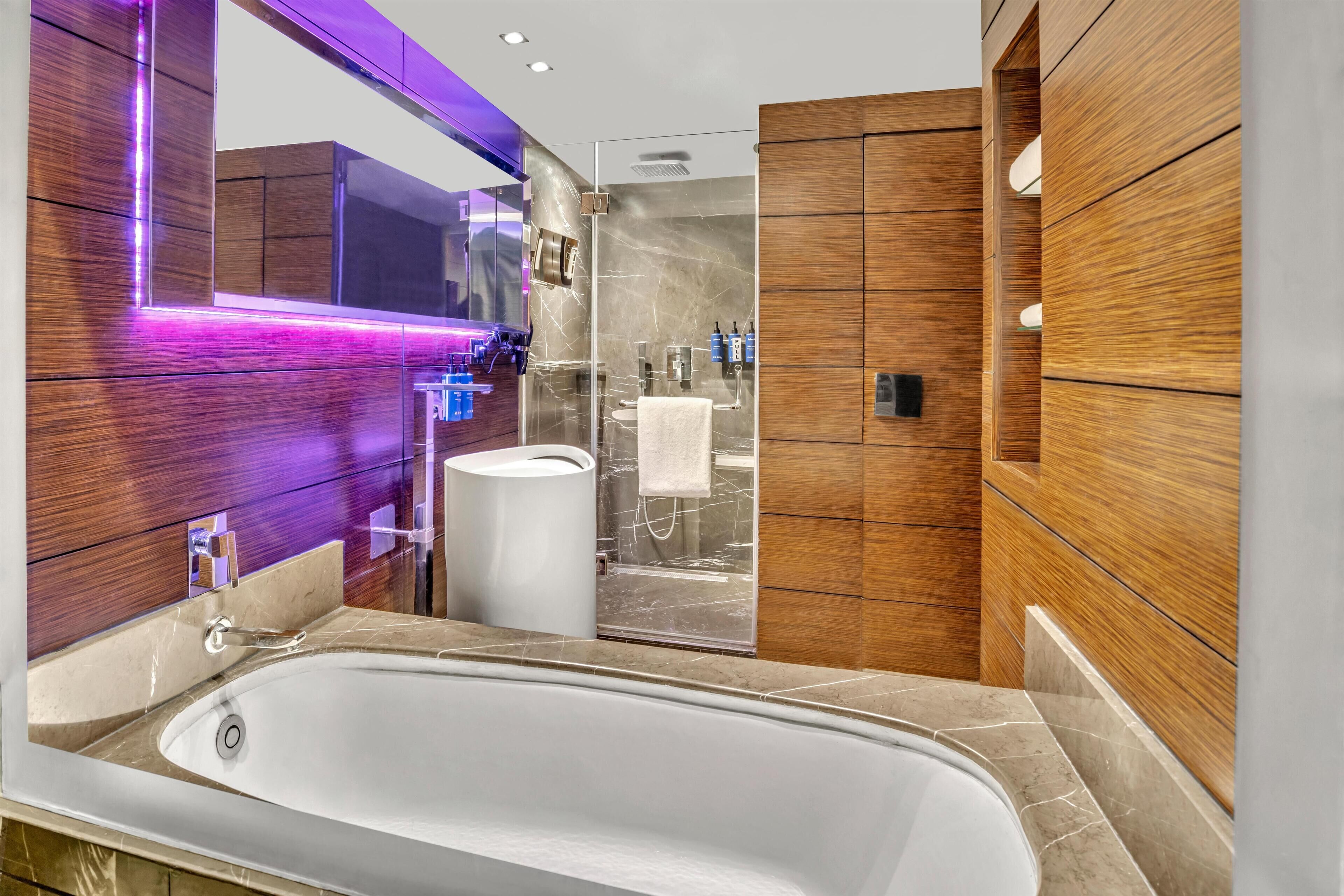 A modern bathroom with a freestanding bathtub, a large mirror, and wooden paneling.