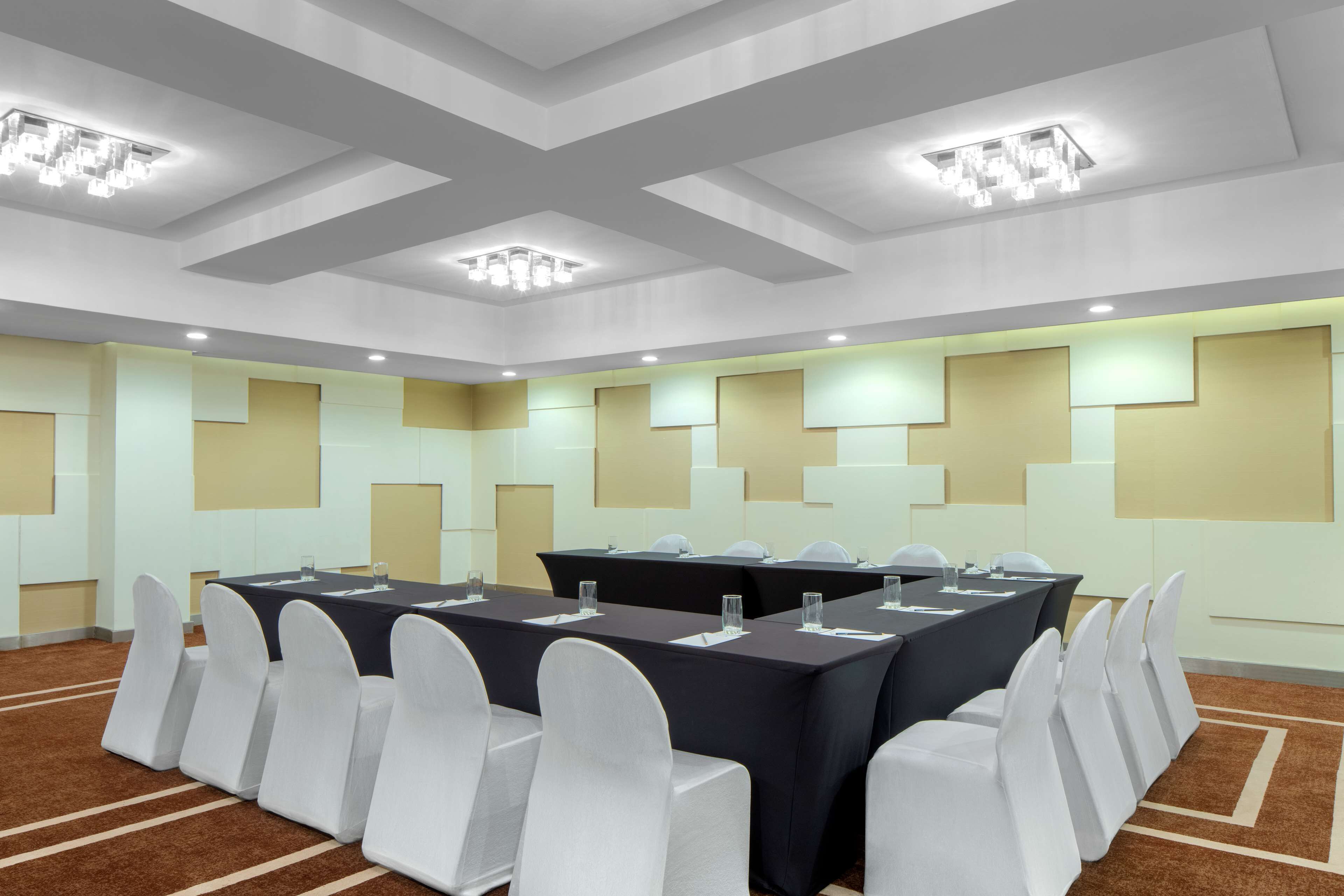 A conference room with a long table, white chairs, and recessed lighting.