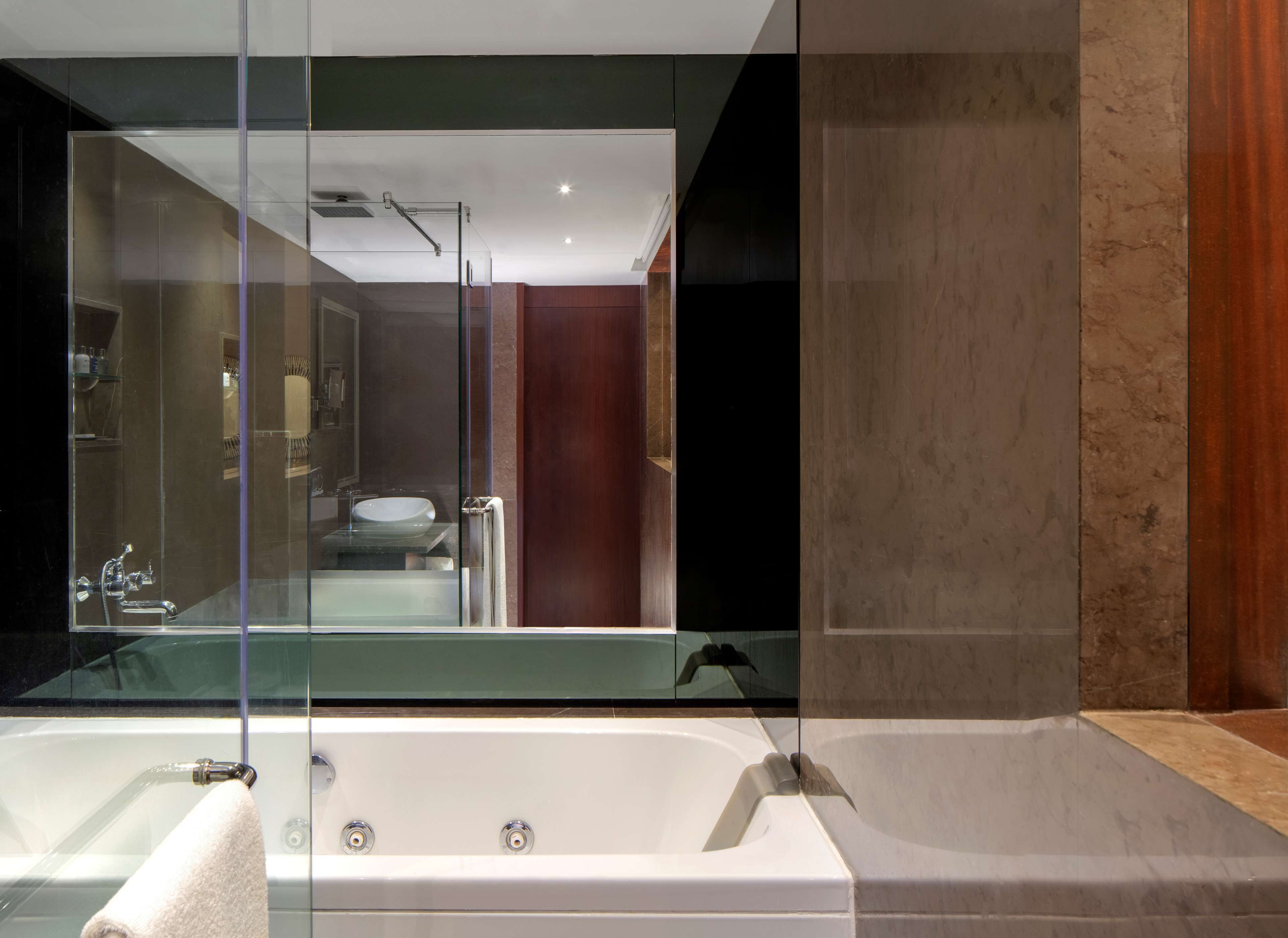 Een moderne badkamer met een douchecabine van glas, een vrijstaand bad en een zichtbare wastafelruimte.