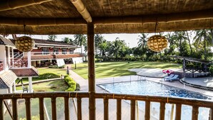 Zona de piscina con vista a una casa y palmeras.