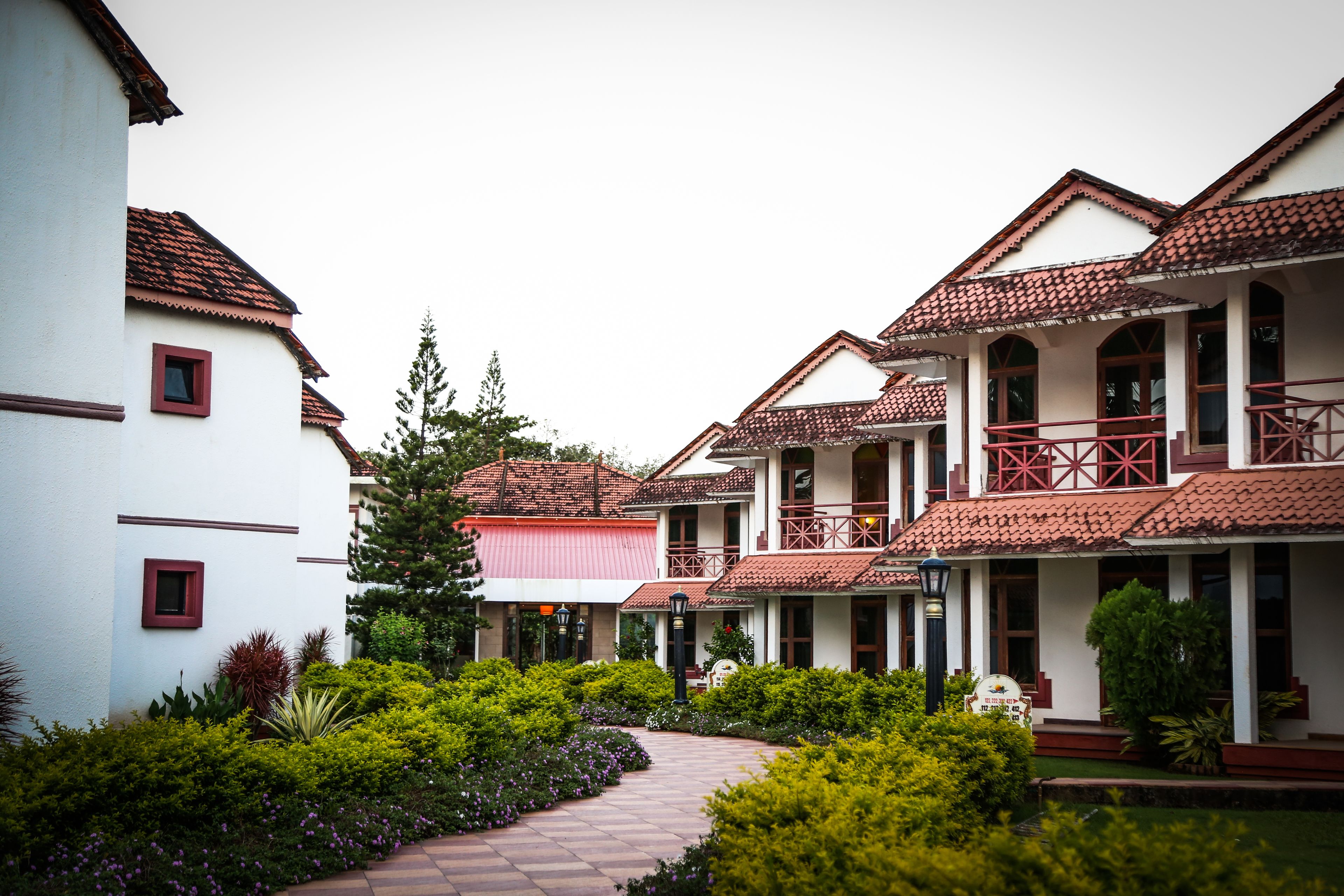 A courtyard with a pathway, surrounded by buildings with red-tiled roofs and white walls.