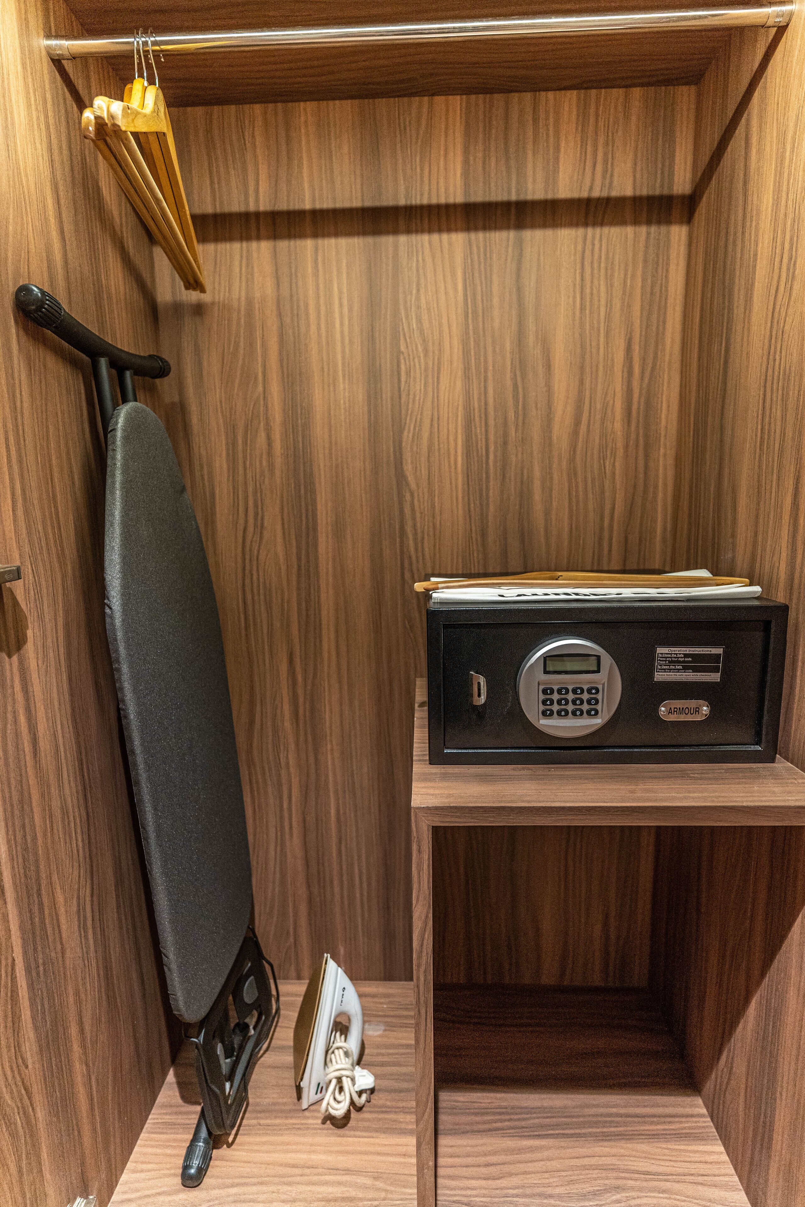 A wooden room with a black iron, a safe, and a hanging clothes rack.
