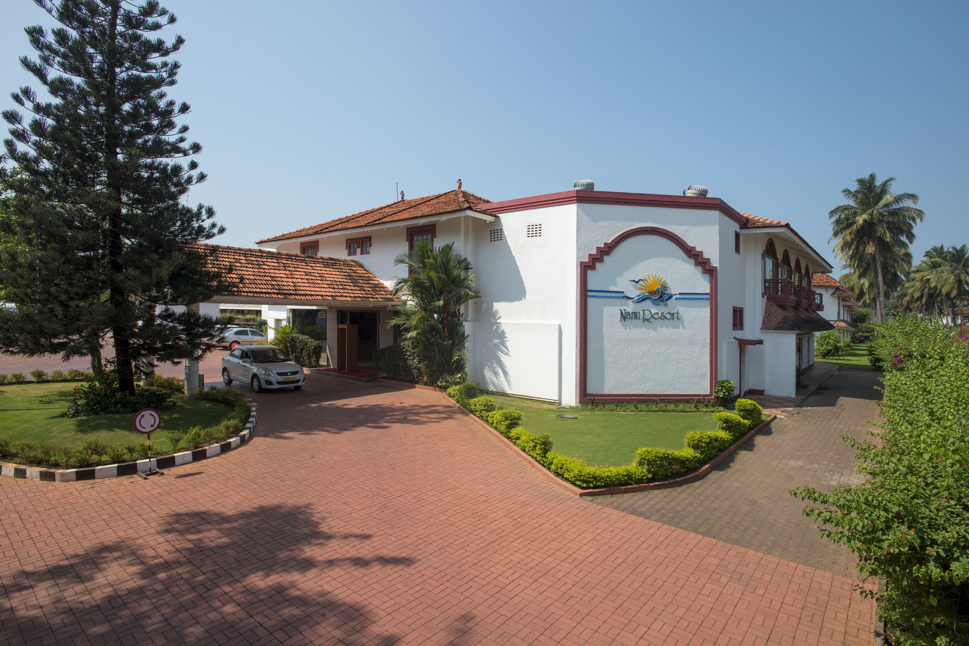 A resort building with a tiled roof, a sign reading "Nam Lu Resort," and a paved driveway leading to the entrance.