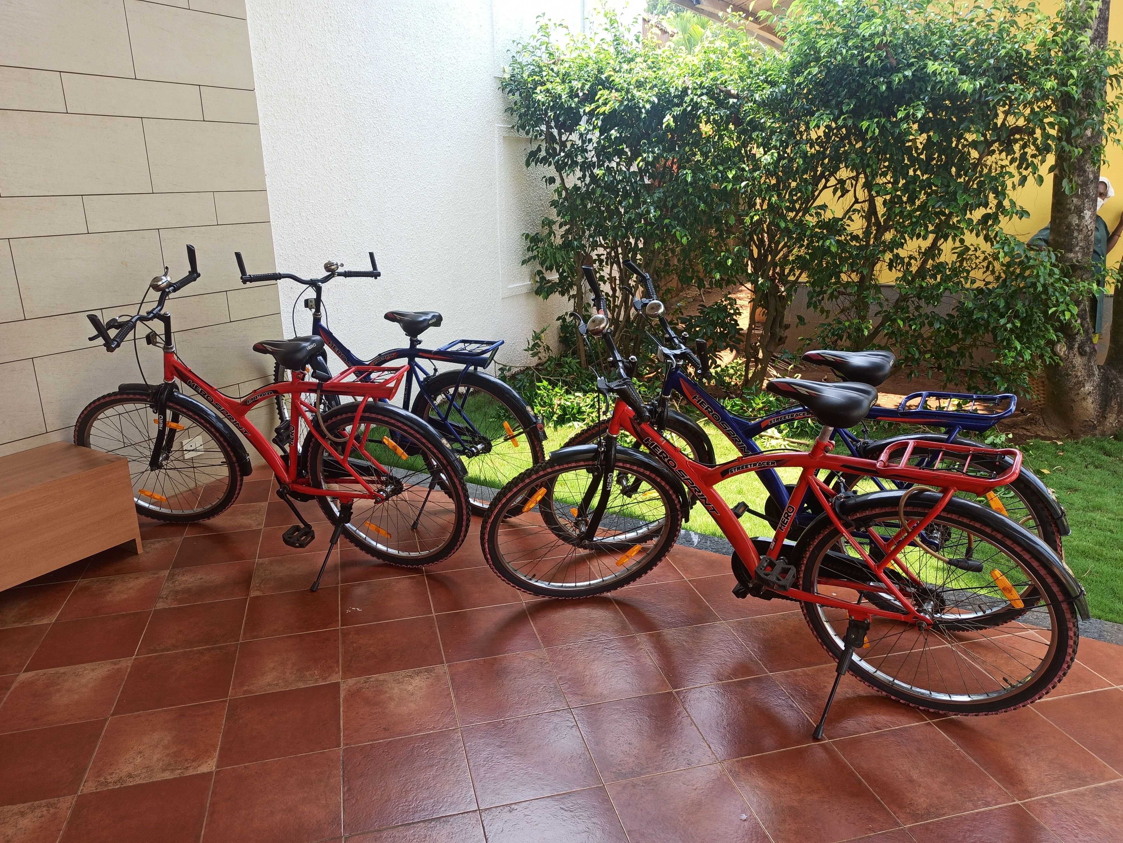 A patio area with tiled flooring, a bench, and several bicycles parked against a wall.