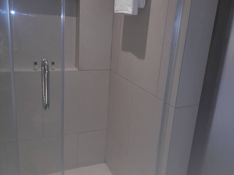 A modern shower stall with a glass door, a towel rack, and a shower control panel.