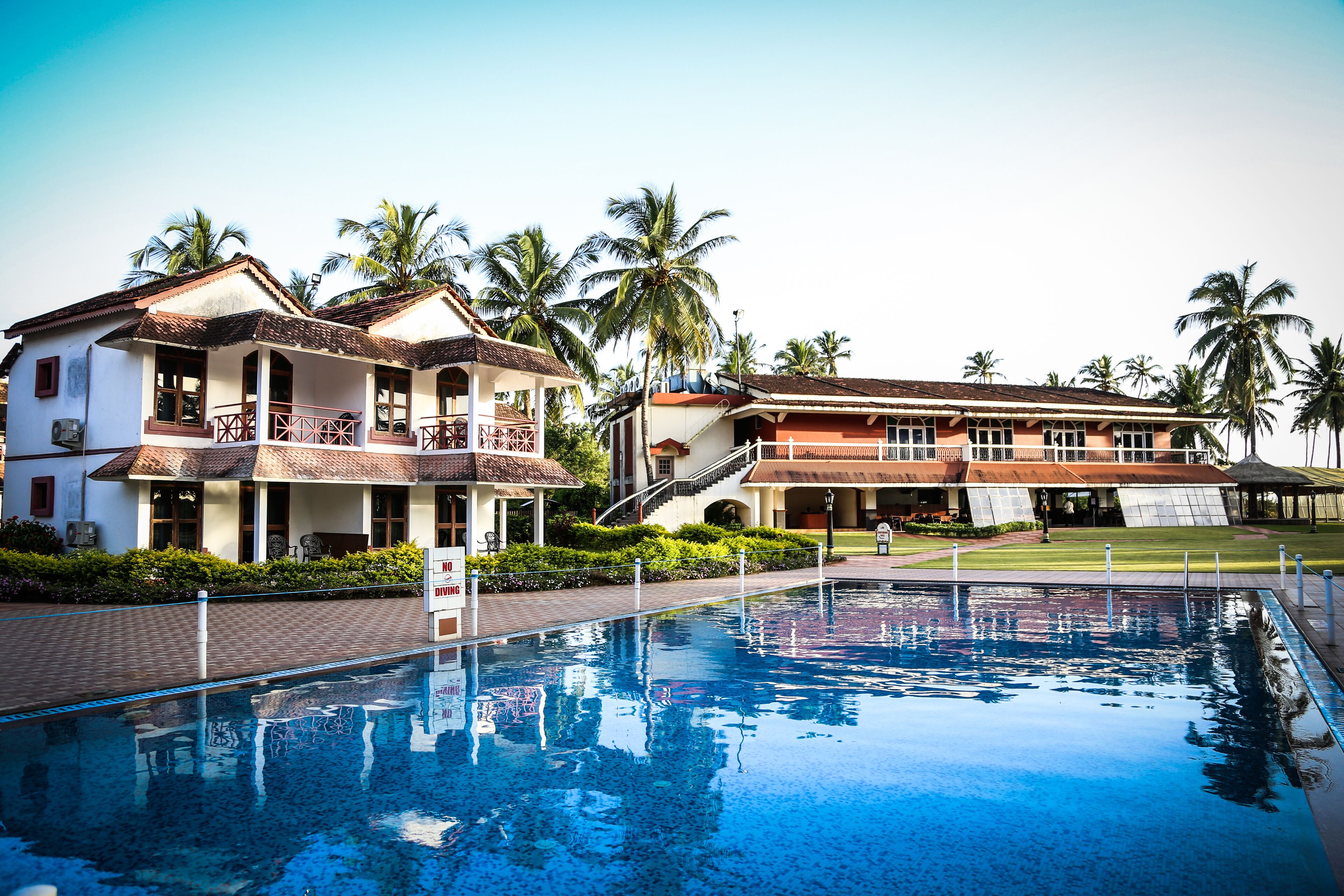 A hotel with a swimming pool, multiple buildings, and palm trees.