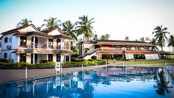 A hotel with a swimming pool, multiple buildings, and palm trees.