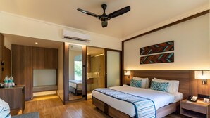 Habitación de hotel con una cama grande, mesitas de noche, ventilador de techo y un espejo.