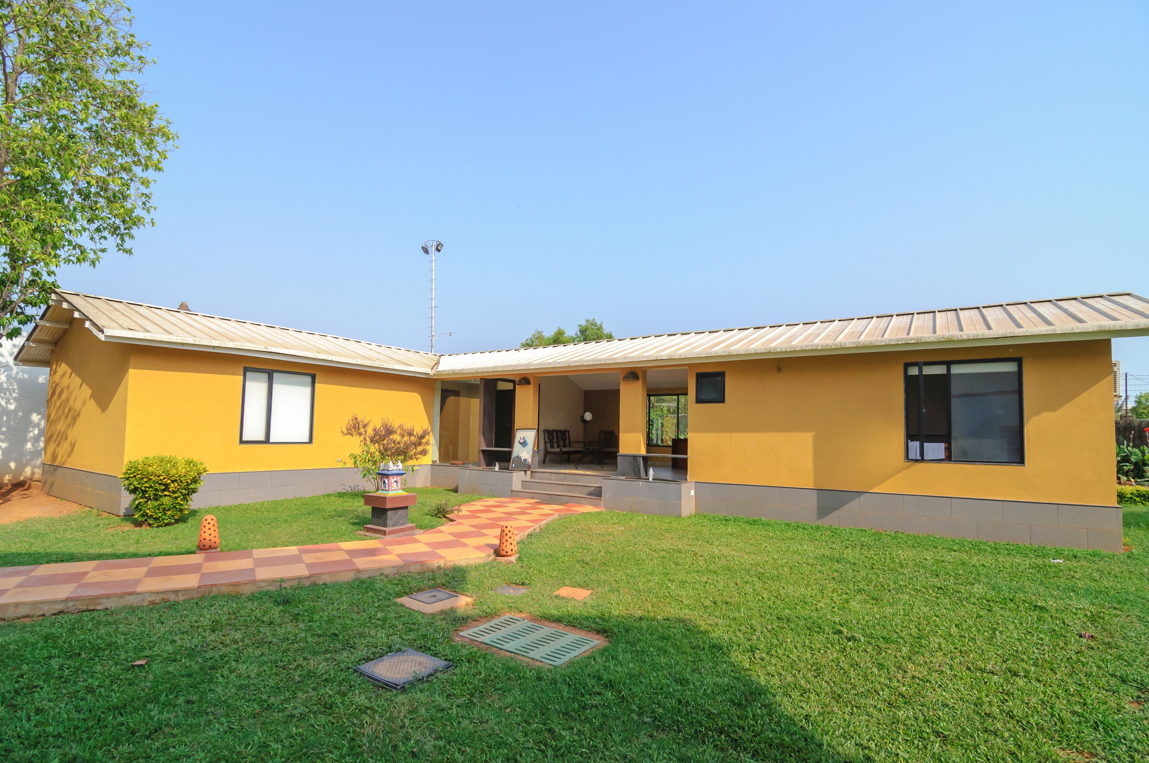 A modern two-story building with a yellow facade, a covered patio, and a well-maintained lawn.