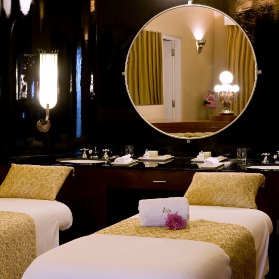 A hotel room with two beds, a large mirror, and a vanity with a sink.