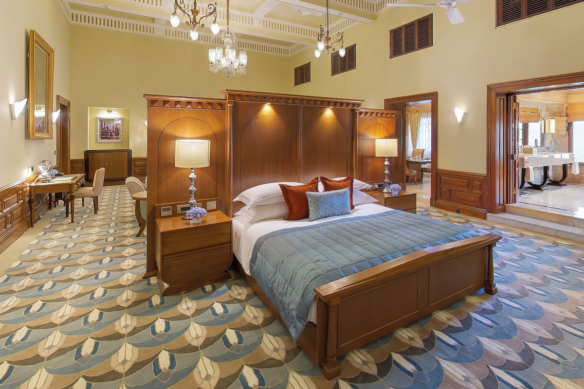 A spacious hotel room with a large bed, a desk, and a chair.
