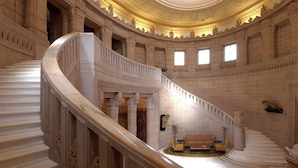 Eine prächtige Treppe mit aufwendiger Geländerkonstruktion und einer luxuriösen Sofagarnitur am Fuß.
