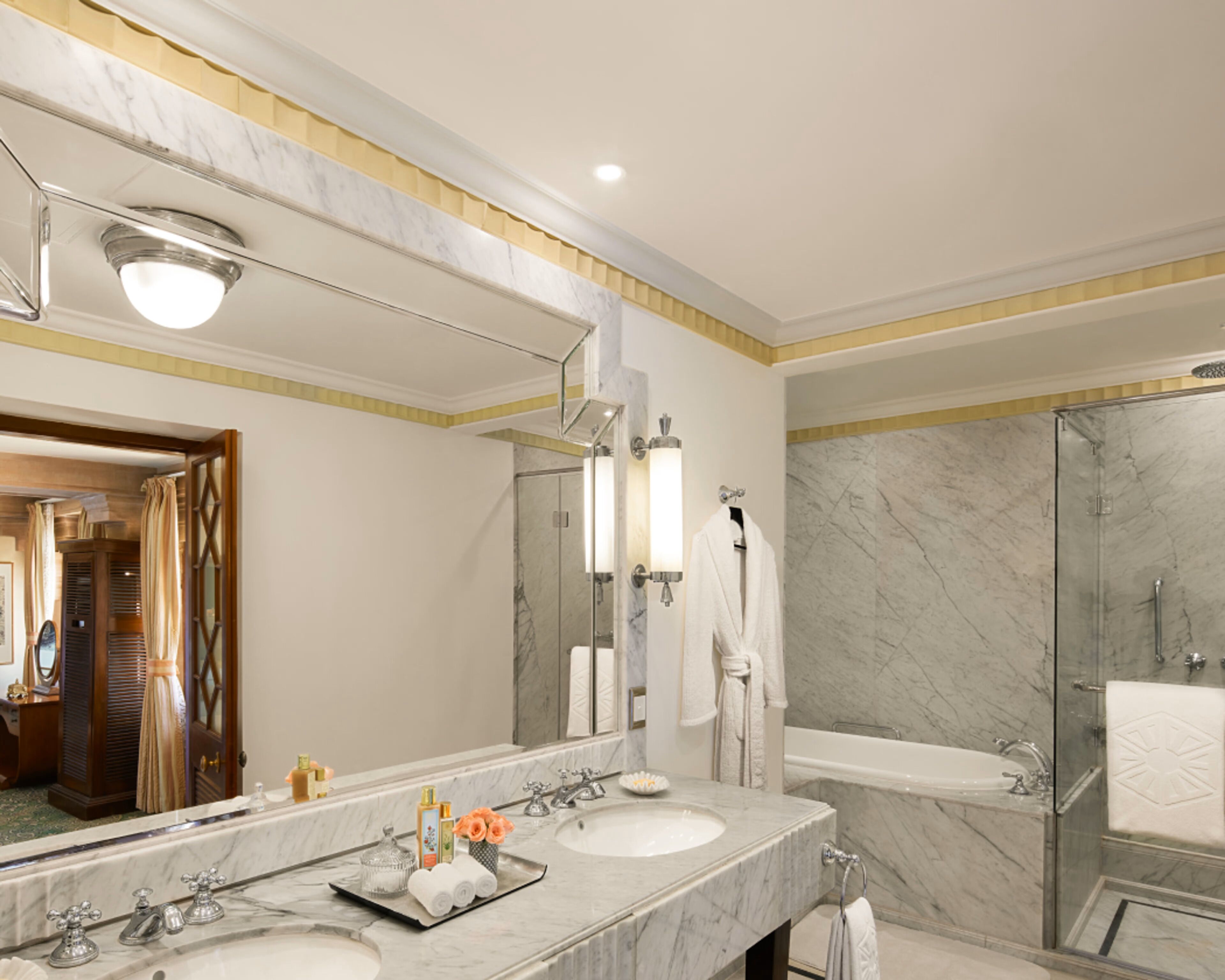 A modern bathroom with a marble vanity, a large mirror, a bathtub, and a glass-enclosed shower.
