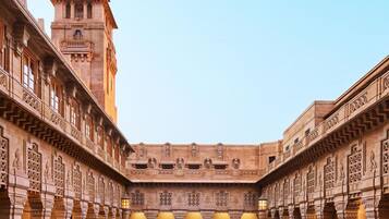 A courtyard with a central fountain, surrounded by ornate buildings with detailed carvings and a prominent tower.