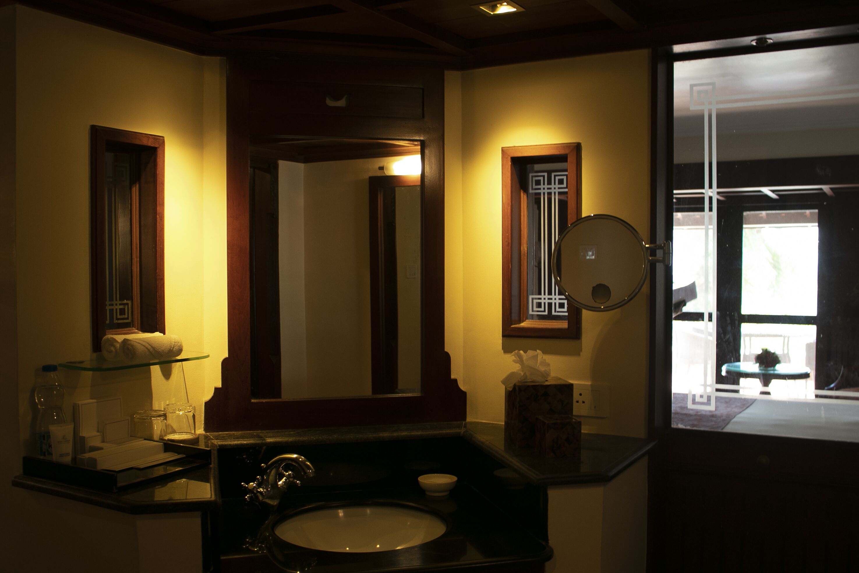 Un baño con lavamanos, espejo y repisa de vidrio.