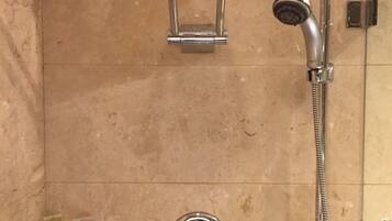 Un baño con ducha, cabezal de ducha de mano y grifo empotrado.
