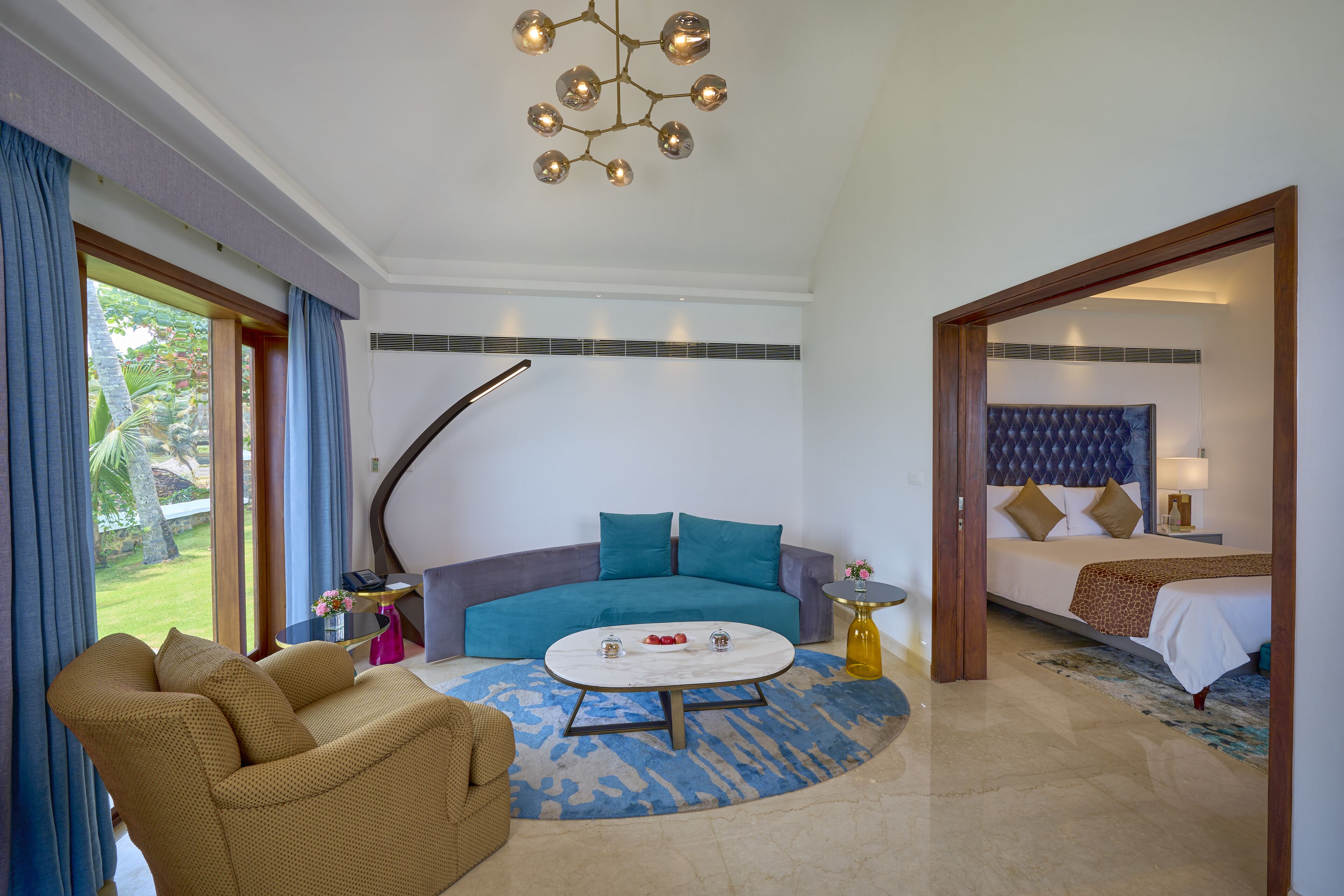 A modern living room with a sofa, a coffee table, and a bed in the adjacent room.