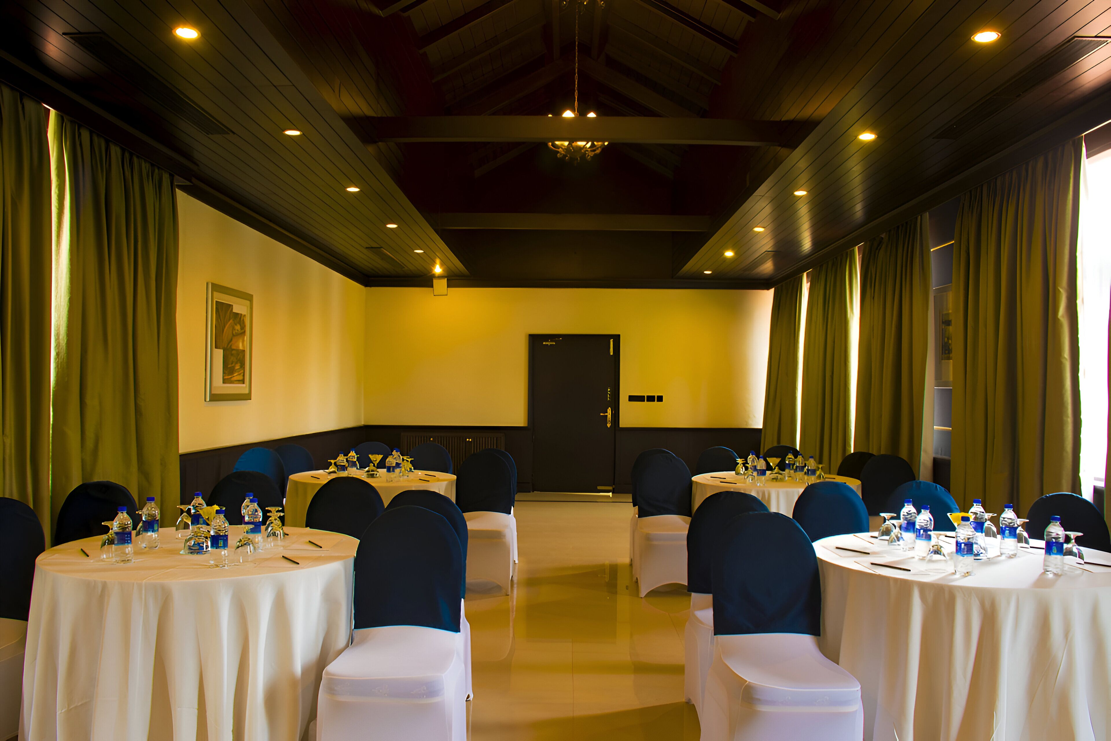A conference room with round tables, chairs, and water bottles.