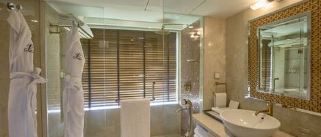 A modern bathroom with a glass-enclosed shower, a large sink, and a mirror with a decorative frame.