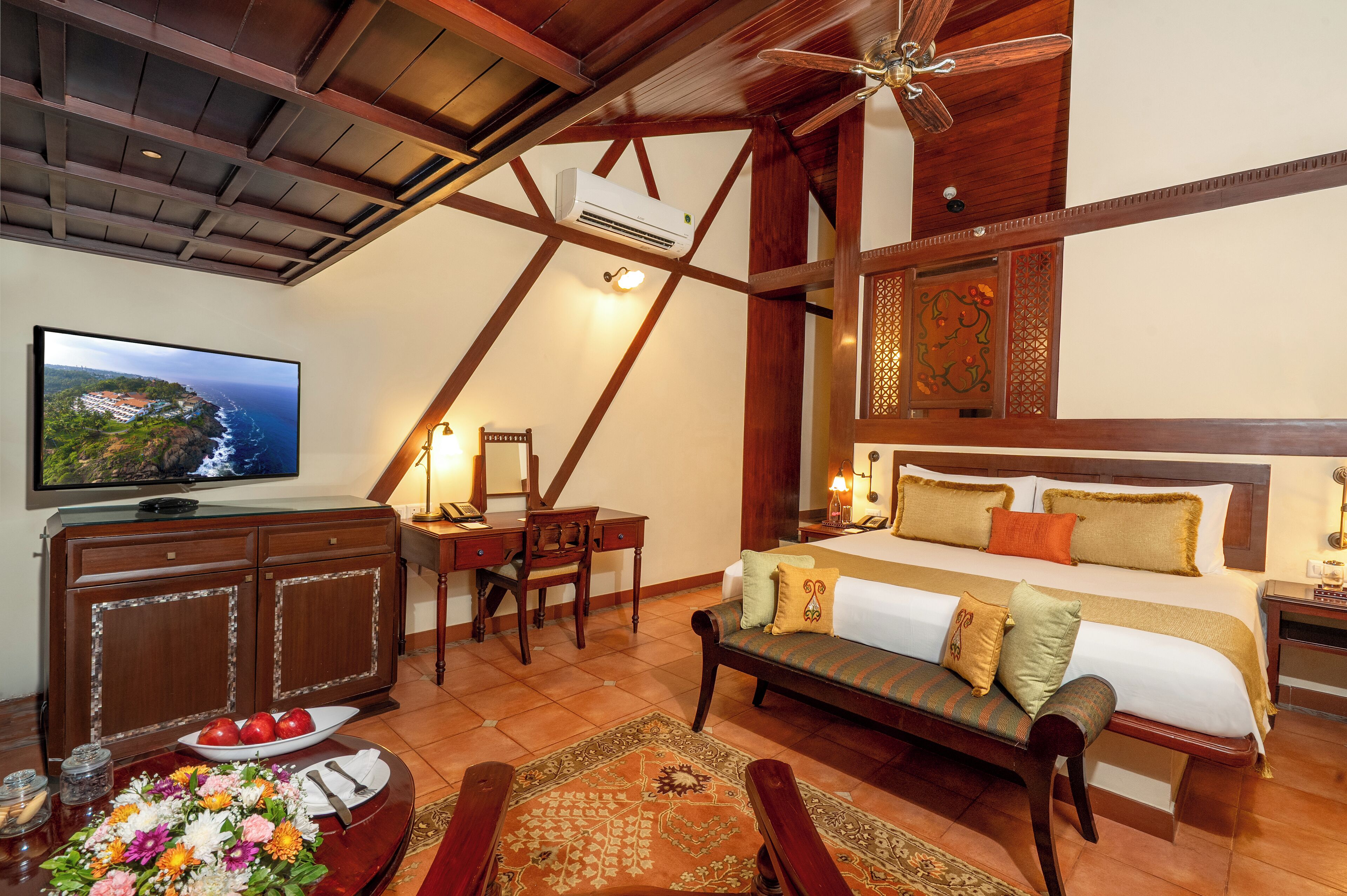 A hotel room with a bed, a desk, a television, and a dining area with a table set for two.