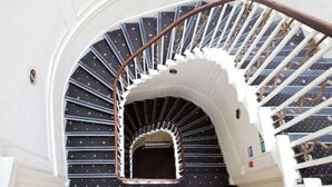 A spiral staircase with a white railing and dark patterned steps. - Rose Court Hotel (London)