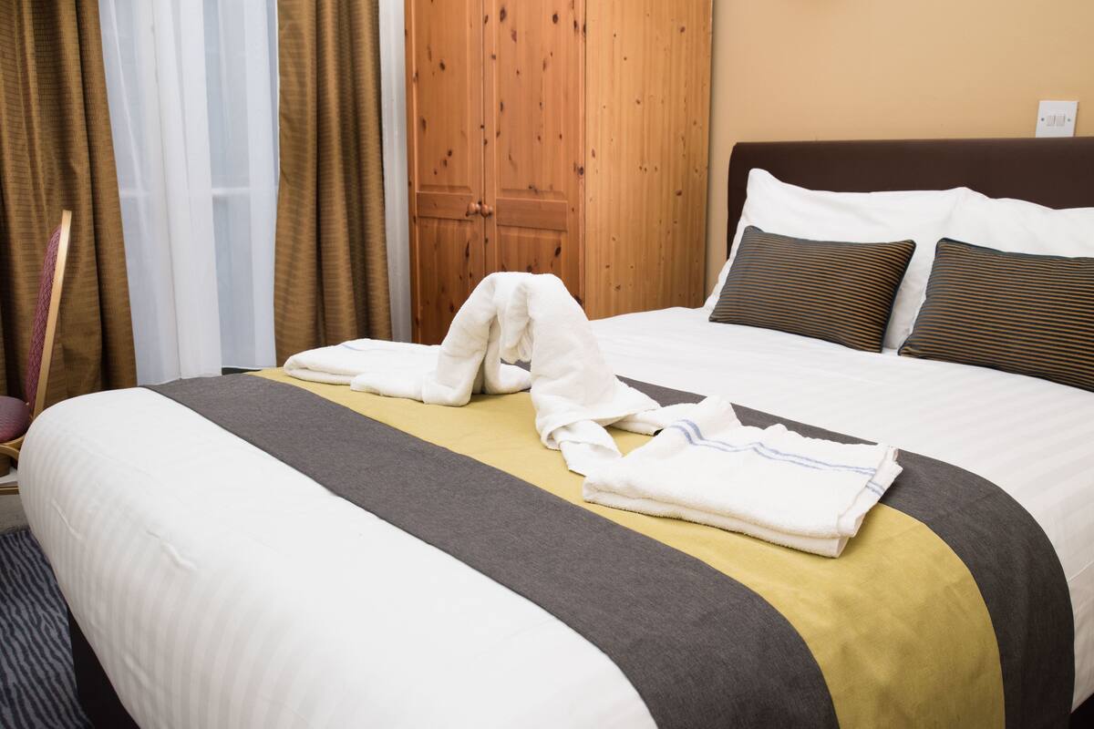 A neatly made bed with a striped pillow, a folded towel, and a blanket.