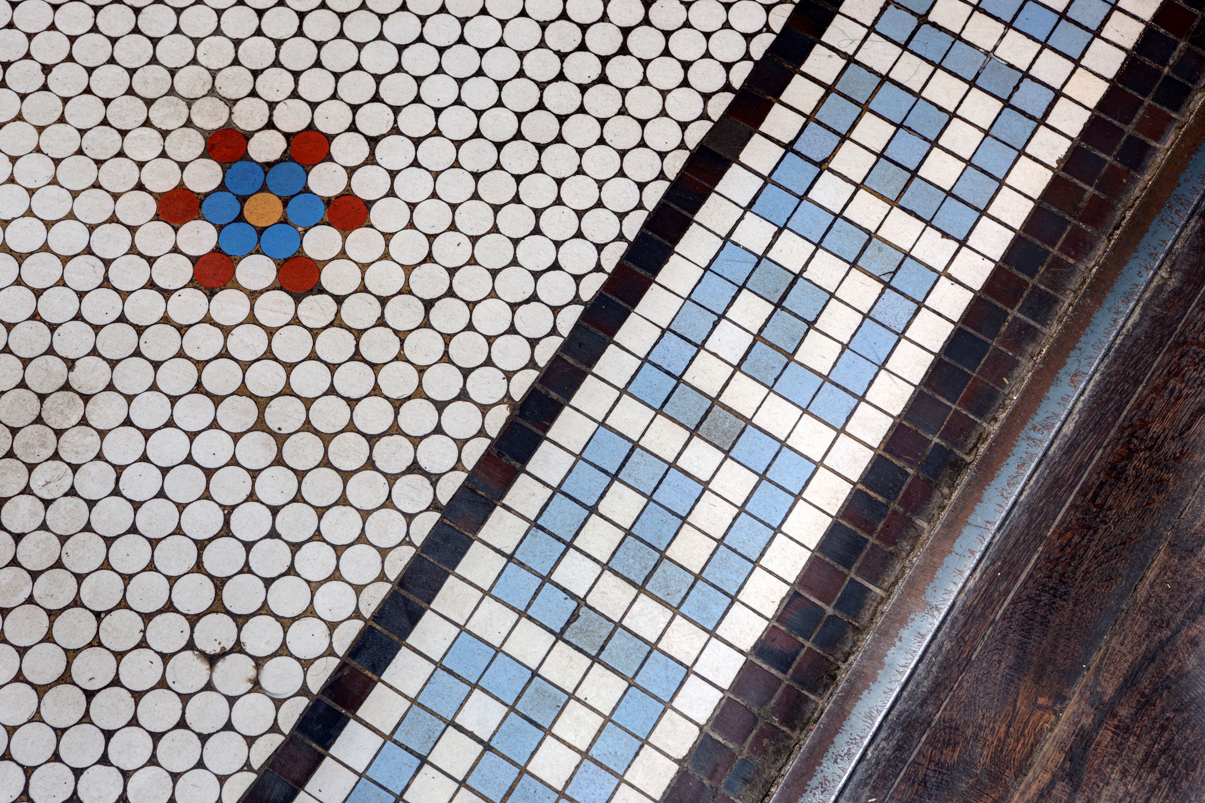 A close-up of a tiled floor with a pattern of white, blue, and red tiles.