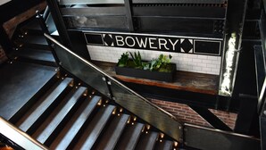 A staircase with a metal railing and a sign that reads "BOWERY".