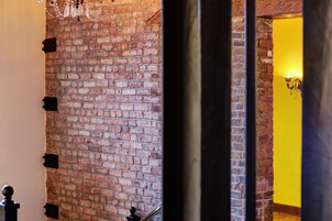 A brick wall with a chandelier and a yellow door.