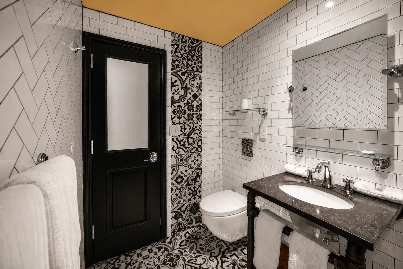 Een badkamer met een zwarte deur, een wit toilet en een wastafel met een spiegel erboven.