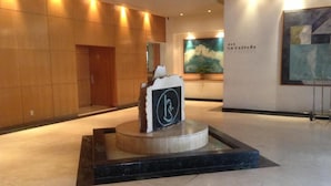 A lobby with a central water feature, a wooden wall, and a painting on the right. - Hotel Sevilla (Mexico City)