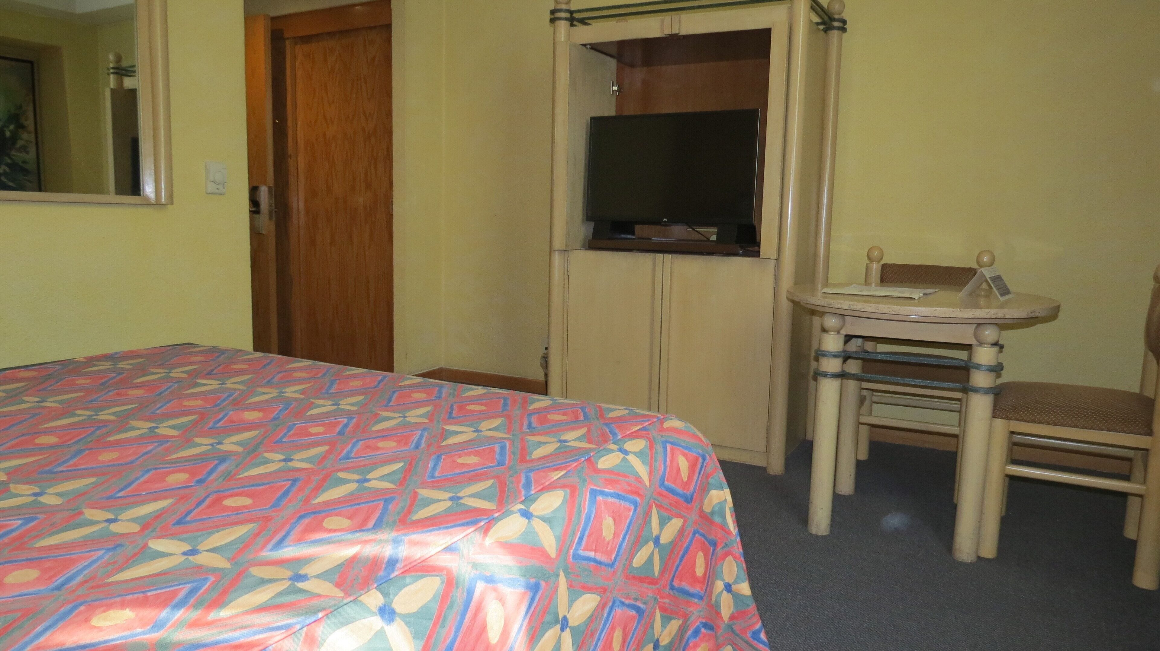 A hotel room with a bed, a TV, a small table, and a chair.