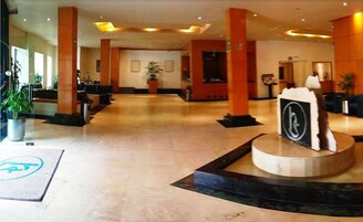 Spaziosa hall con soffitti alti, ampie colonne e una reception centrale.